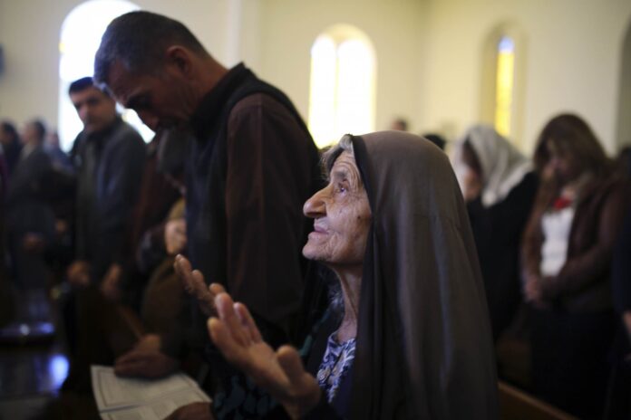 An Iraqi Christian woman prays during a mass on Christmas day at Mar Girgis Church in Baghdad