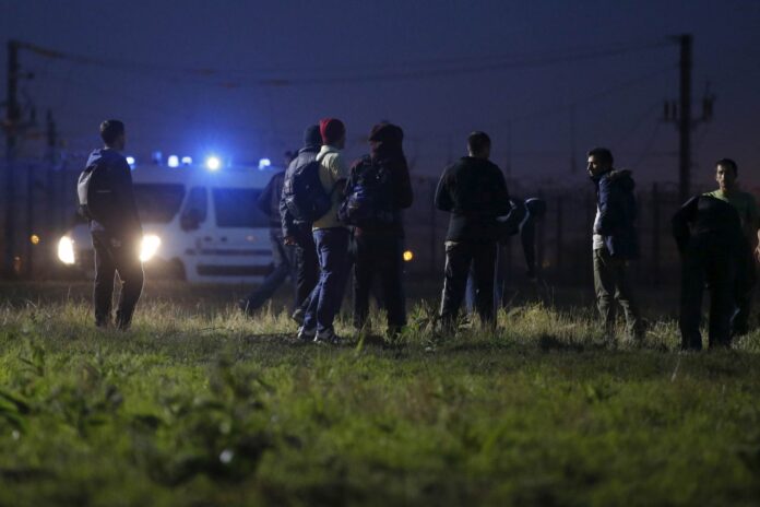 Migrants walk close to a Eurotunnel fence, as police arrive in a van, during an attempt to access the Channel Tunnel in Frethun, near Calais