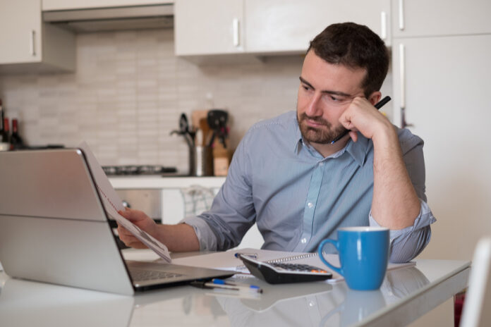 Frustrated Man Calculating Bills And Tax Expenses