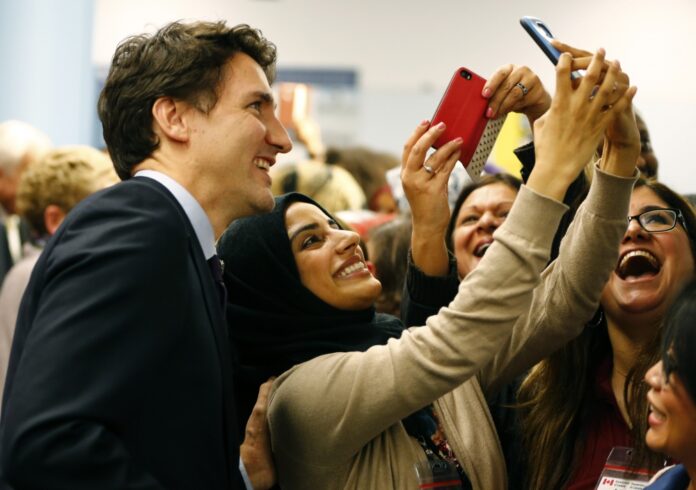Canada's Prime Minister Justin Trudeau poses with airport staff as they await Syrian refugees to arrive at the Toronto Pearson International Airport