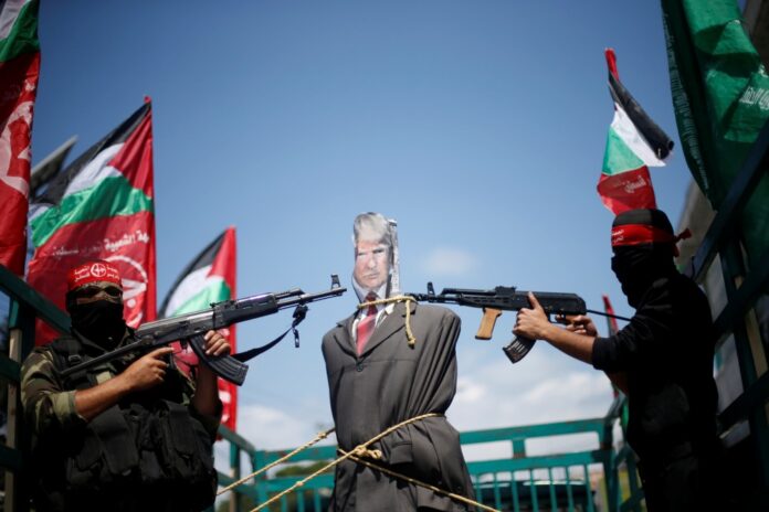 Palestinian militants from the Popular Front for the Liberation of Palestine (PFLP) aim their weapons at an effigy depicting U.S. President Donald Trump, in Gaza City