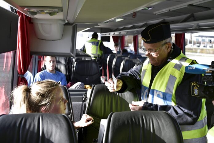 A police officer checks passports inside a bus at Lernacken, on the Swedish side of the Oresund strait