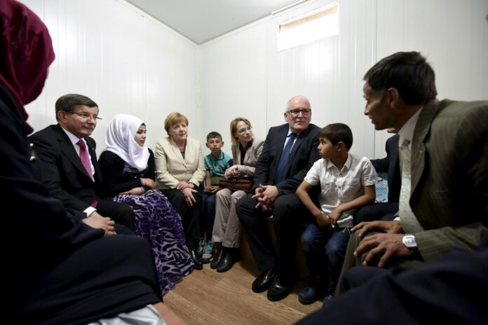 German Chancellor Merkel, Turkish Prime Minister Davutoglu and European Commission Vice-President Timmermans speak with Syrian refugee Sayadi and his family in Nizip refugee camp