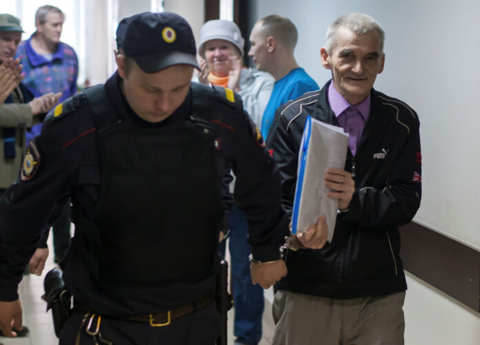Historian Yuri Dmitriev is escorted by a police officer upon his arrival for a court hearing in Petrozavodsk