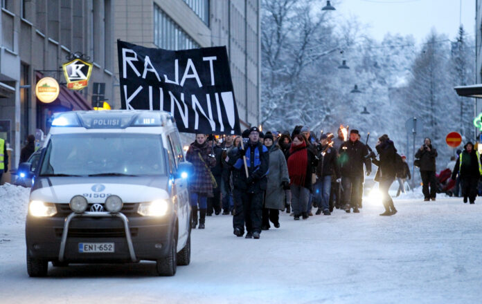 Anti-immigration marchers are led by a police van on the streets in Tampere
