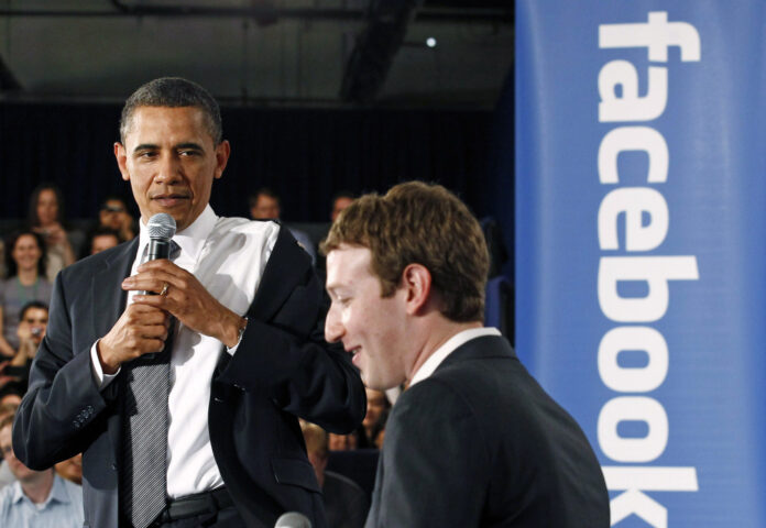 U.S. President Barack Obama takes off his jacket as he attends a town hall meeting at Facebook headquarters with CEO Mark Zuckerberg in Palo Alto