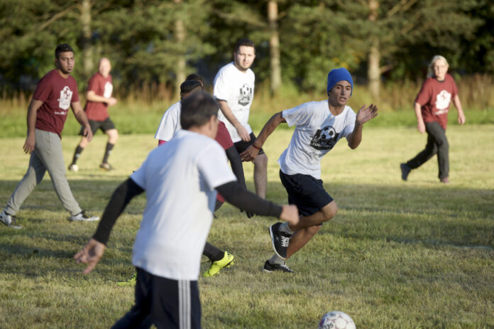 Asylum seekers and locals play soccer during the