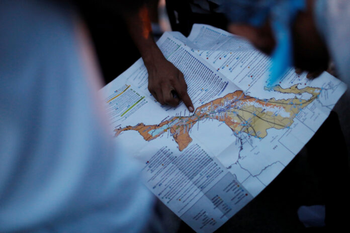 A migrant, part of a caravan of thousands traveling from Central America en route to the United States, points at a map while rest in Santiago Niltepec