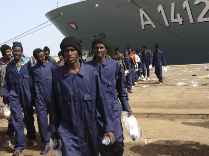 Migrants walk on the dock after disembarking from the German naval vessel Frankfurt Am Main in the Sicilian harbour of Augusta