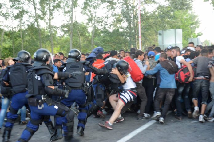 Hungarian riot police charge migrants at the border crossing with Serbia in Roszke