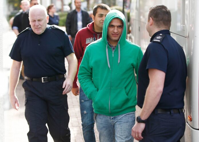 UK Border Force staff escort the first group of unaccompanied minors from the Jungle migrant camp in Calais to be brought to Britain as they arrive at an immigration centre in Croydon, south London