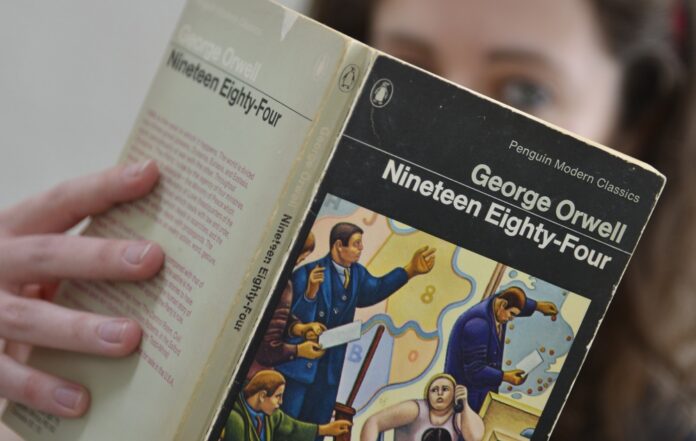 Laura Wood of Skoob Books poses for a photograph with a copy of George Orwell's '1984' in central London