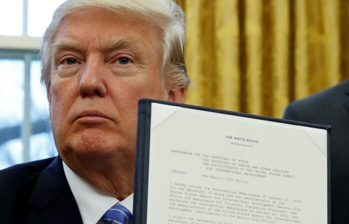 U.S. President Donald Trump holds up his executive order on the reinstatement of the Mexico City Policy after signing it in the Oval Office of the White House in Washington