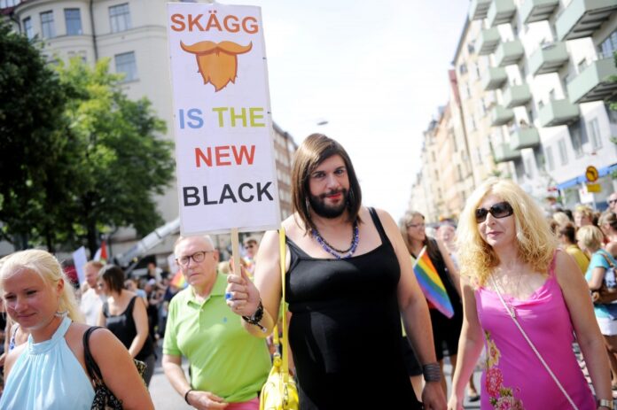 A man dressed as Austrian Eurovision Song Contest 2014 winner Conchita Wurst holds up a sign that reads,