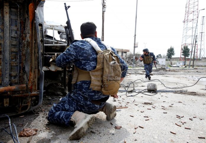 Federal police members take cover during a battle with Islamic State fighters at Bab al Beed district in the old city of Mosul,