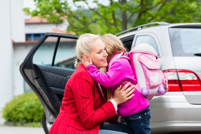 Mother consoling daughter on first day at school, the kid being