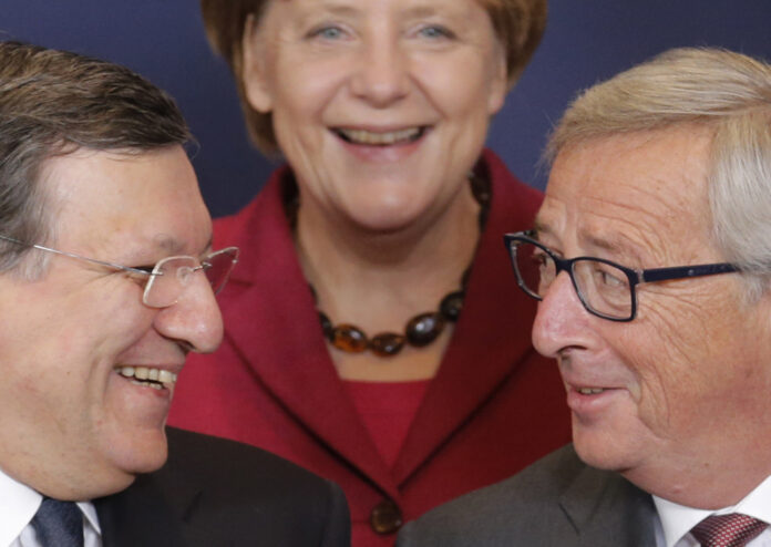 Germany's Chancellor Merkel smiles as she poses for a family photo next to incoming president of the European Commission Juncker and outgoing president Barroso during an EU summit in Brussels