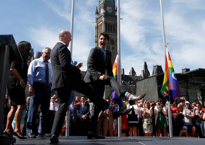 Canada's Prime Minister Justin Trudeau compares socks with Liberal MP Randy Boissonnault during a pride flag raising ceremony on Parliament Hill in Ottawa, Ontario