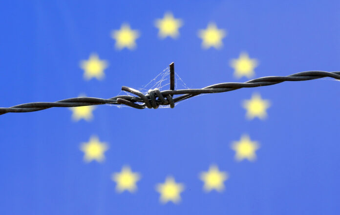A barbed wire is seen in front of European Union flag iin an immigration reception centre in Bicske