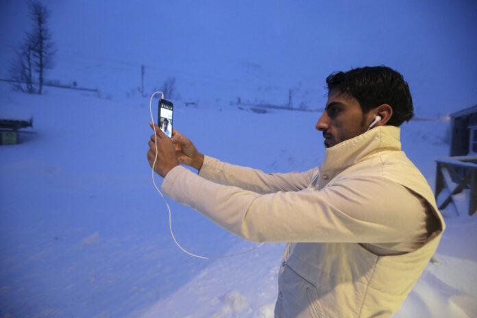 A refugee takes a selfie at the front of his camp at a hotel touted as the world's most northerly ski resort in Riksgransen
