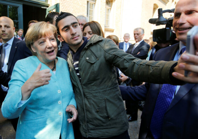 FILE PHOTO: Syrian refugee Anas Modaman takes a selfie with German Chancellor Angela Merkel outside a refugee camp near the Federal Office for Migration and Refugees after registration at Berlin's Spandau district