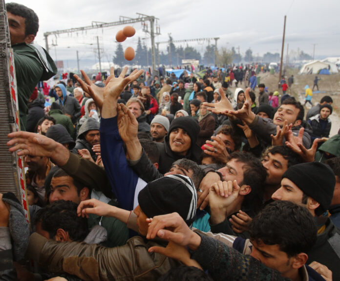 Migrants try to get products from a truck at a makeshift camp on the Greek-Macedonian border near the village of Idomeni