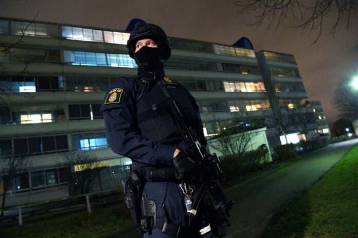 A policeman looks on after an object exploded next to a police station in Rosengard, Malmo