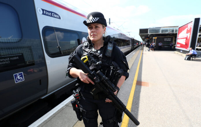 An armed police officer patrols on a platform at Milton Keynes station