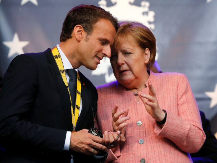 FILE PHOTO: French President Emmanuel Macron speaks with German Chancellor Angela Merkel after being awarded the Charlemagne Prize for